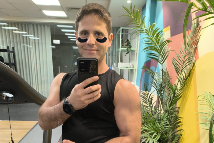 Man taking a mirror selfie in a modern office setting with plants.